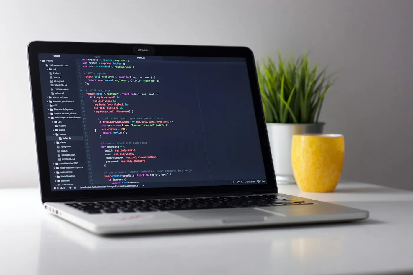 A laptop showing code on a clean white desk.