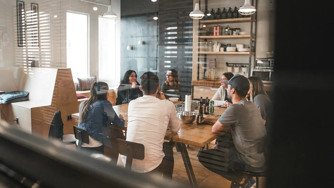 A team meeting around a long table in a bright studio.
